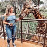 East Africa group trip for young travelers with a California travel influencer feeding a giraffe at Giraffe Centre Kenya